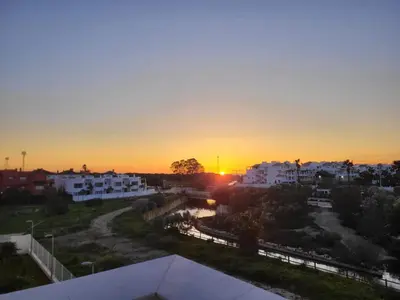 a sunset over a city with white buildings at ÁTICOS ROTA Punta Candor in Rota