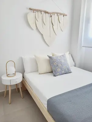 a white bedroom with a bed and a chair at ÁTICOS ROTA Punta Candor in Rota