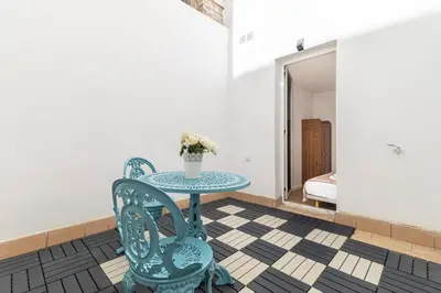 a table with two chairs and a vase with flowers on it at Allo Apartments Santa Maria II Centro 2 Habitaciones in Jerez de la Frontera