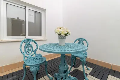 a blue table with two chairs and a vase of flowers at Allo Apartments Santa Maria II Centro 2 Habitaciones in Jerez de la Frontera