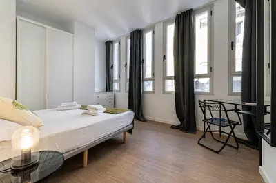 a bedroom with a bed and a table and windows at Allo Apartments Santa Maria II Centro 2 Habitaciones in Jerez de la Frontera