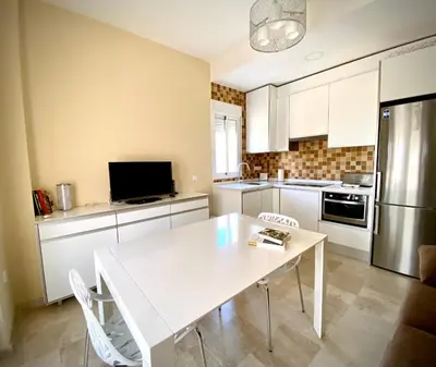 a kitchen with a white table and a refrigerator at MyChoice Meninas in Rota