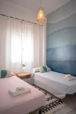 a bedroom with two beds and a chandelier at Apartamento con terraza privada en el centro del Puerto de Santa María in El Puerto de Santa María