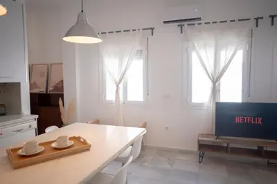 a white kitchen with a table and a tv at Apartamento con terraza privada en el centro del Puerto de Santa María in El Puerto de Santa María