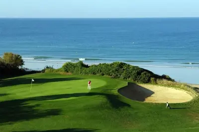 two people on a golf course with the ocean in the background at bamboo & golf house in Campano
