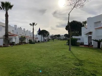 a green yard with palm trees and white buildings at bamboo & golf house in Campano