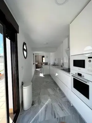 a kitchen with white walls and marble floors at Ático céntrico con terraza privada y plaza de garaje in Sanlúcar de Barrameda