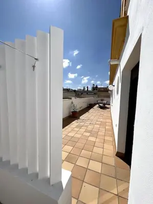 a balcony with white walls and a tile floor at Ático céntrico con terraza privada y plaza de garaje in Sanlúcar de Barrameda
