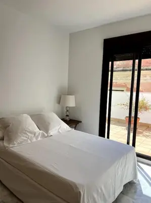a white bed in a white room with a window at Ático céntrico con terraza privada y plaza de garaje in Sanlúcar de Barrameda