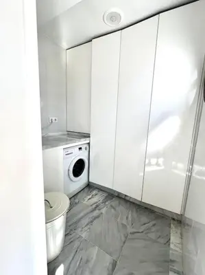 a white bathroom with a washing machine and a toilet at Ático céntrico con terraza privada y plaza de garaje in Sanlúcar de Barrameda