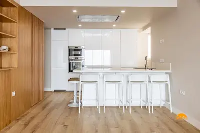 a kitchen with white cabinets and bar stools at Malibu by Cadiz Time in Cádiz
