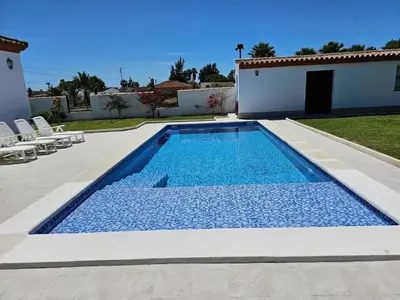 a swimming pool in a yard with chairs and a house at Charming villa in Chiclana de la Frontera with private pool in Chiclana de la Frontera