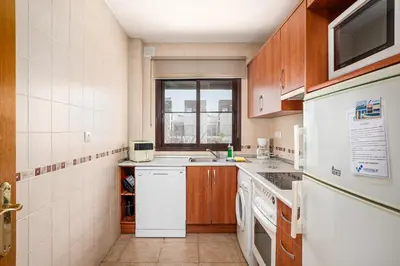 a kitchen with a white refrigerator and a sink at Apartamento familiar muy soleado cerca de la playa y parking incluido in Chiclana de la Frontera