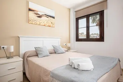 a bedroom with a bed with two towels on it at Apartamento familiar muy soleado cerca de la playa y parking incluido in Chiclana de la Frontera