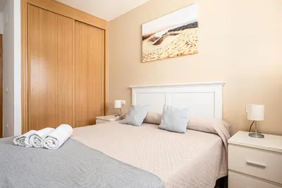a bedroom with two beds and a picture of a beach at Apartamento familiar muy soleado cerca de la playa y parking incluido in Chiclana de la Frontera