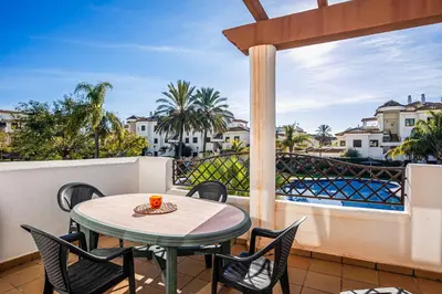 a patio with a table and chairs on a balcony at Apartamento familiar muy soleado cerca de la playa y parking incluido in Chiclana de la Frontera