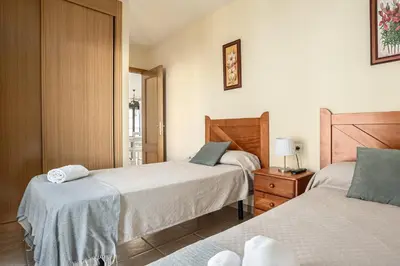a bedroom with two beds and a dresser with a lamp at Apartamento familiar muy soleado cerca de la playa y parking incluido in Chiclana de la Frontera