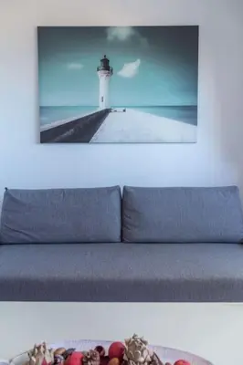 a picture of a couch with a lighthouse in the background at El Beduino by Gades Gestión in Cádiz
