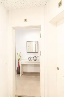 a white hallway with a mirror and a table at El Beduino by Gades Gestión in Cádiz