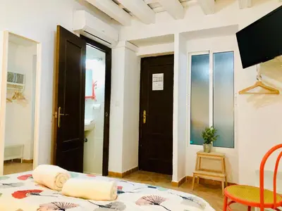 a room with a bed and a door and a table at Pensión La Cantarera in Cádiz
