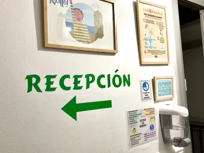 a reception sign on a wall with a green arrow at Pensión La Cantarera in Cádiz