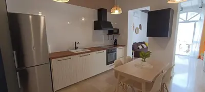 a kitchen with a table and a stainless steel refrigerator at Apartamento Pale Cream in Jerez de la Frontera