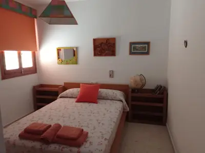 a bedroom with a bed with a red pillow on it at Cruces, piso en pleno centro urbano in Sanlúcar de Barrameda