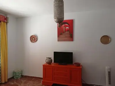 a living room with a tv on a wooden dresser at Cruces, piso en pleno centro urbano in Sanlúcar de Barrameda