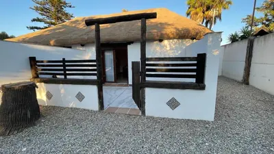 a small white house with a thatched roof at Casa del lago in Sanlúcar de Barrameda