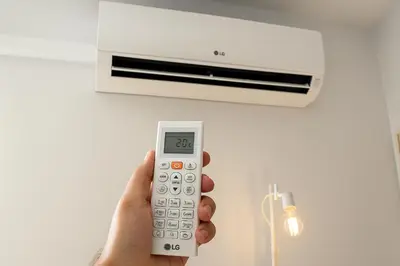 a hand holding a remote control in front of a air conditioner at Skyline - Beach apartment with breathtaking views and more in Cádiz
