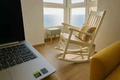 a chair and a laptop in a room with a window at Skyline - Beach apartment with breathtaking views and more in Cádiz