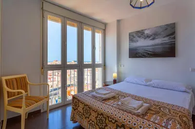 a bedroom with a bed and a chair and windows at Cielo gaditano in Cádiz