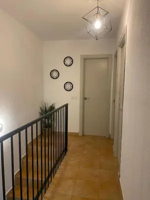 a hallway with two clocks on the wall and stairs at Apartamento La Balconera 1ª línea de Playa in Chiclana de la Frontera