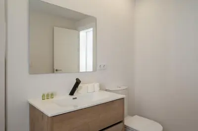a bathroom with a sink and a mirror and a toilet at Apartoyou - Enamorados in El Puerto de Santa María