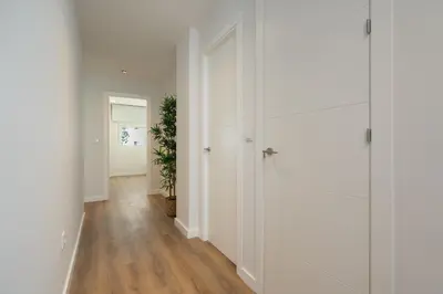 a hallway with white walls and wooden floors and a plant at Apartoyou - Enamorados in El Puerto de Santa María