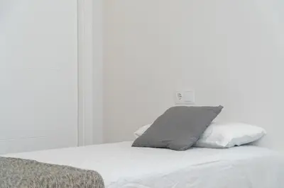 a white bed with a gray pillow on it at Apartoyou - Enamorados in El Puerto de Santa María