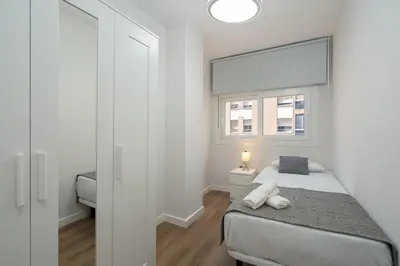a white bedroom with a bed and a window at Apartoyou - Enamorados in El Puerto de Santa María