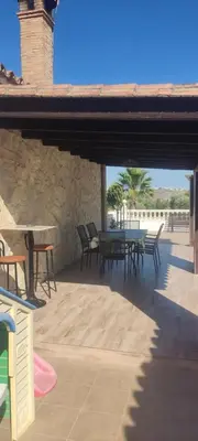 a patio with a table and chairs and a stone wall at Las Vistas in Arcos de la Frontera
