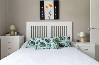 a bedroom with a white bed with green and white pillows at Al lado de la victoria in Cádiz