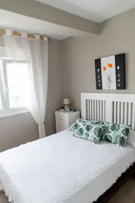a bedroom with a white bed with pillows and a window at Al lado de la victoria in Cádiz