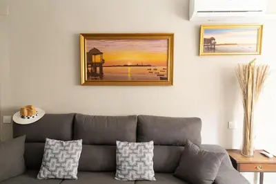 a living room with a gray couch and a picture on the wall at Al lado de la victoria in Cádiz