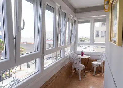 a room with windows and a table and chairs at Al lado de la victoria in Cádiz