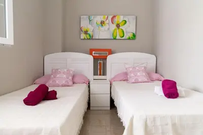two white beds with pink pillows in a room at Al lado de la victoria in Cádiz