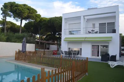 a white house with a pool and a fence at Villa Cristal in Chiclana de la Frontera