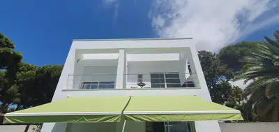 a white building with a green umbrella in front of it at Villa Cristal in Chiclana de la Frontera