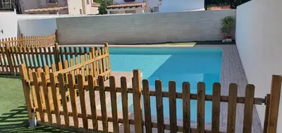a wooden fence next to a blue swimming pool at Villa Cristal in Chiclana de la Frontera