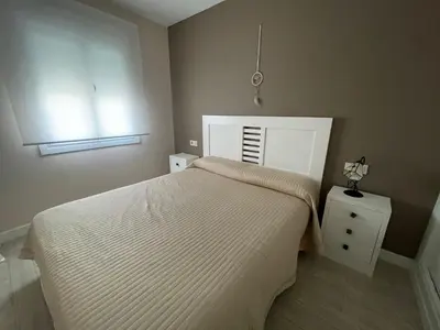 a small bedroom with a bed and a night stand at Apartamento de Reme Playa de la Barrosa in Chiclana de la Frontera