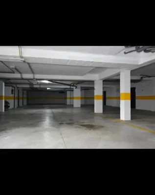 an empty parking garage with white and yellow columns at Apartamento de Reme Playa de la Barrosa in Chiclana de la Frontera