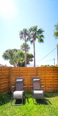 two chairs sitting in the grass in front of a fence at Apartamento Mery Oliva in Chiclana de la Frontera