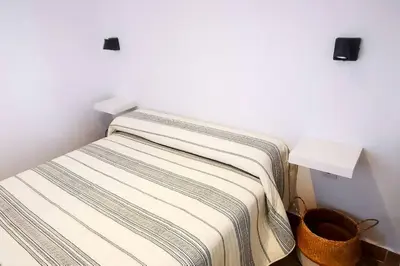 a bed with a striped blanket in a room at Apartamento Mery Oliva in Chiclana de la Frontera